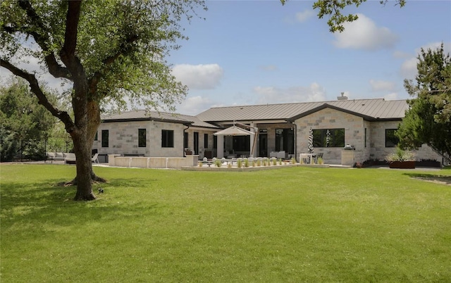 7817 Orisha Dr, Austin, TX 78739 - rear view of house with a yard, stone siding, metal roof, a patio, and a standing seam roof
