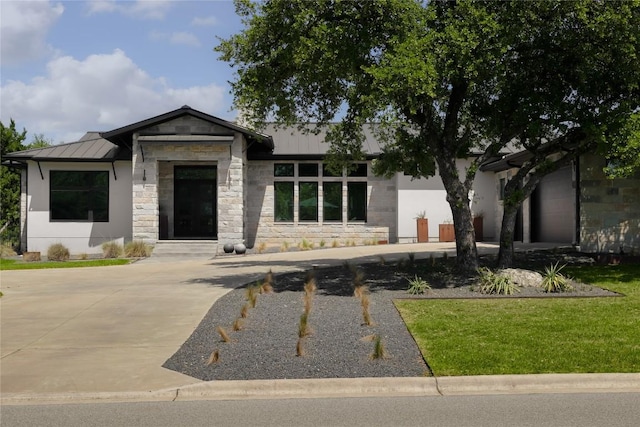 7817 Orisha Dr, Austin, TX 78739 - prairie-style house with a front yard, stone siding, metal roof, and a standing seam roof