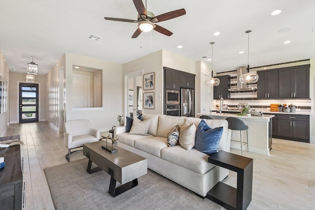 living area with baseboards, recessed lighting, a ceiling fan, visible vents, and light wood finished floors