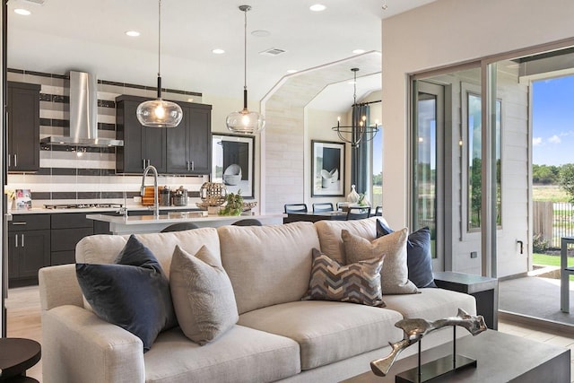 living room with visible vents, light wood finished floors, an inviting chandelier, and recessed lighting