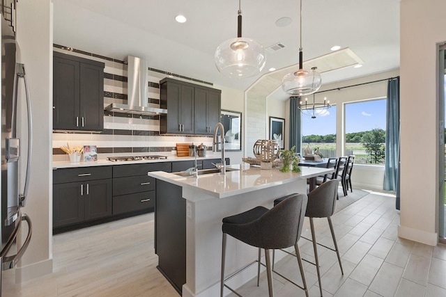 kitchen featuring tasteful backsplash, light countertops, appliances with stainless steel finishes, a kitchen breakfast bar, and extractor fan