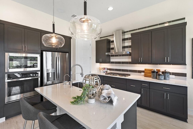 kitchen featuring a sink, ventilation hood, a kitchen bar, stainless steel appliances, and pendant lighting