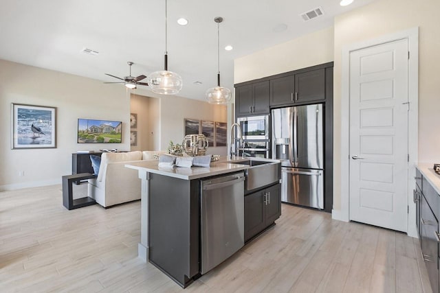 kitchen featuring open floor plan, a ceiling fan, light wood-style floors, visible vents, and appliances with stainless steel finishes