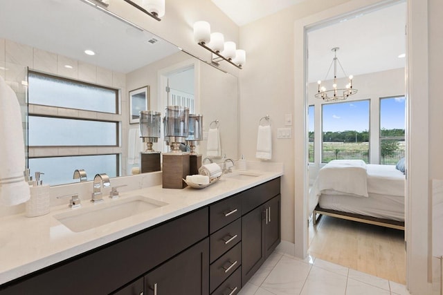 full bath with a sink, ensuite bathroom, double vanity, and a notable chandelier
