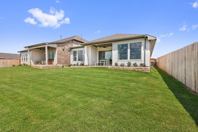rear view of property with a yard, a fenced backyard, and a ceiling fan