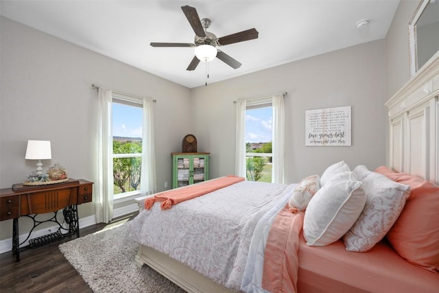 bedroom featuring ceiling fan, multiple windows, baseboards, and dark wood finished floors
