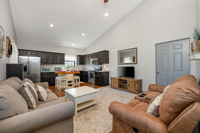 living room with high vaulted ceiling, recessed lighting, and light wood-style floors