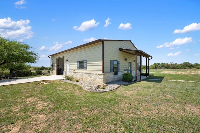 view of side of property with stone siding and a lawn