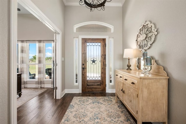 entryway with baseboards, an inviting chandelier, a high ceiling, dark wood-style flooring, and ornamental molding