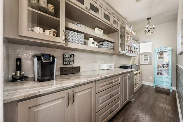 bar featuring pendant lighting, an inviting chandelier, dark wood-type flooring, tasteful backsplash, and baseboards