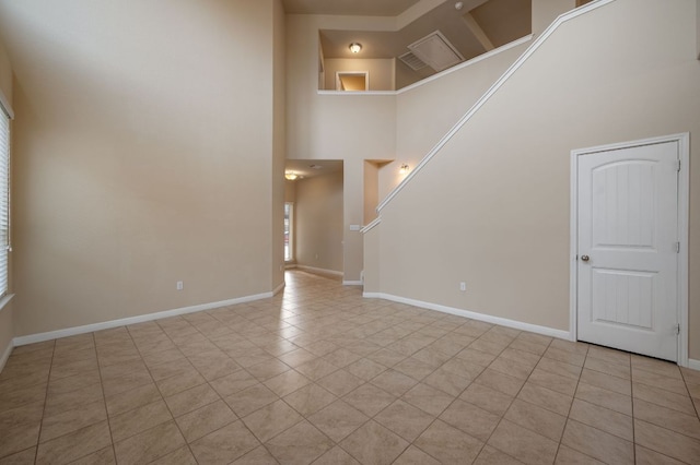 unfurnished living room featuring a high ceiling, light tile patterned floors, and baseboards