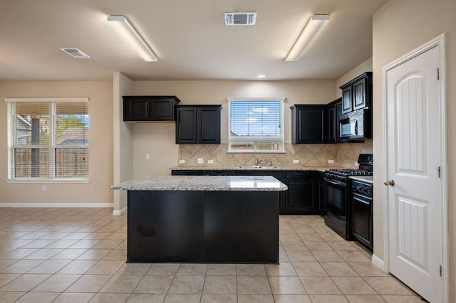 kitchen with visible vents, a sink, black appliances, and a kitchen island