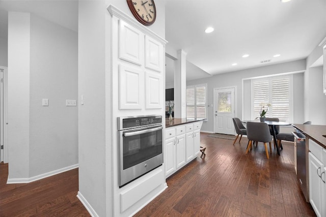 8909 Beatty Ct, Austin, TX 78749 - kitchen featuring appliances with stainless steel finishes, dark wood-style flooring, dark countertops, white cabinetry, and recessed lighting