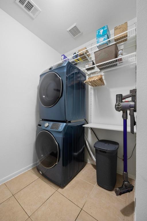 8909 Beatty Ct, Austin, TX 78749 - laundry area featuring stacked washer / dryer, light tile patterned floors, and baseboards