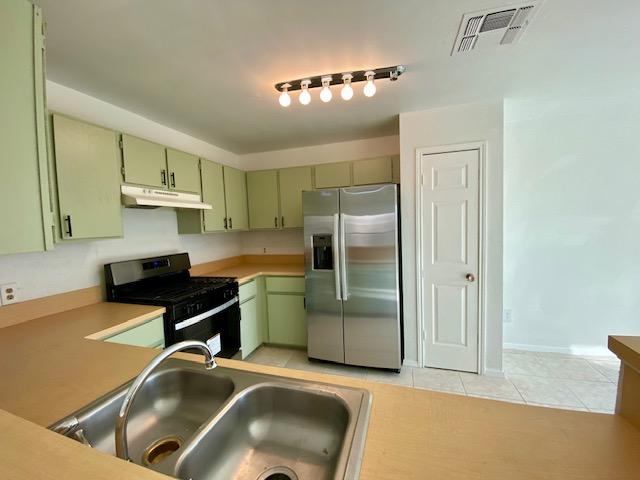 12318 Marogot Run, Austin, TX 78758 - kitchen featuring stainless steel fridge, green cabinetry, range with gas cooktop, and under cabinet range hood