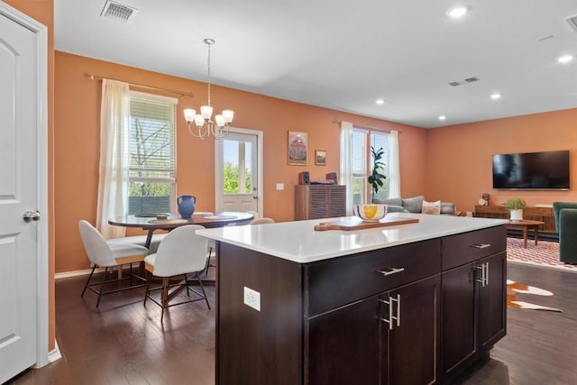 6809 Ellsworth Walk, Austin, TX 78724 - kitchen with dark wood-style flooring, light countertops, a chandelier, pendant lighting, and a center island