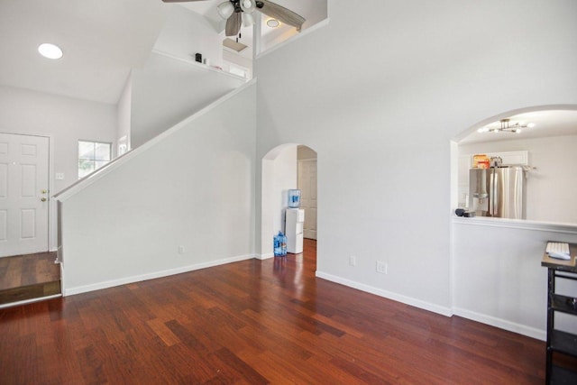 339 Liberty St, Hutto, TX 78634 - unfurnished living room featuring a ceiling fan, arched walkways, wood finished floors, and a high ceiling