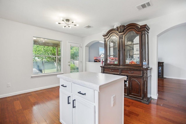 339 Liberty St, Hutto, TX 78634 - kitchen with arched walkways, dark wood finished floors, light countertops, white cabinets, and a kitchen island