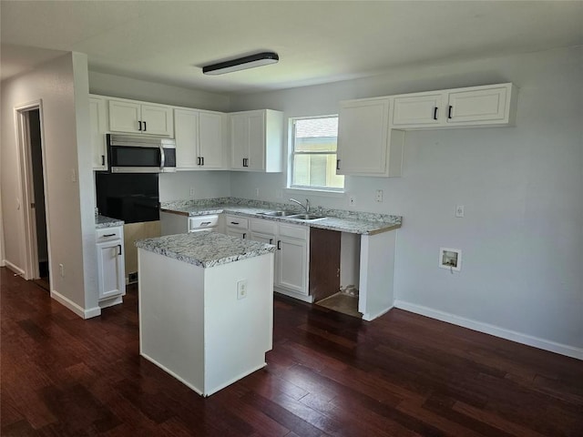 339 Liberty St, Hutto, TX 78634 - kitchen with stainless steel microwave, dark wood-style floors, white cabinetry, and a kitchen island