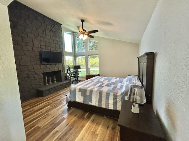 438 Eagle, Lakeway, TX 78734 - bedroom with lofted ceiling, a ceiling fan, wood finished floors, a textured wall, and a fireplace