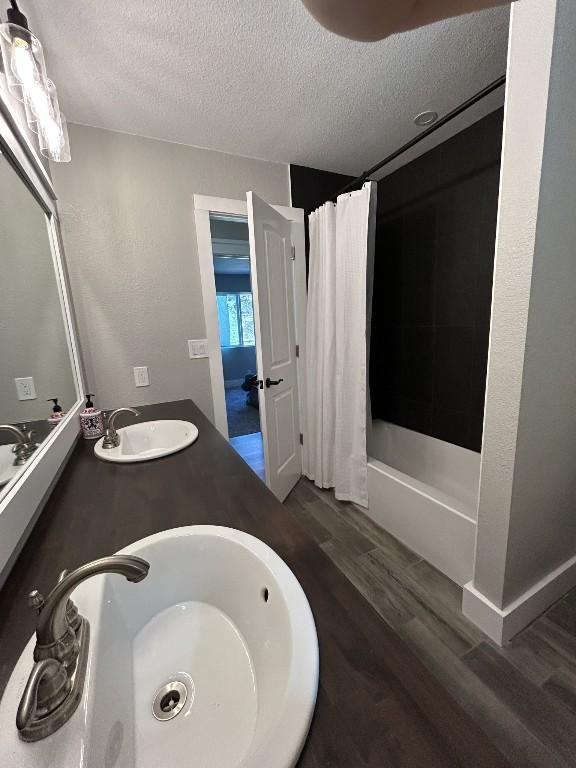 438 Eagle, Lakeway, TX 78734 - full bath featuring shower / tub combo with curtain, a textured ceiling, a sink, and wood finished floors