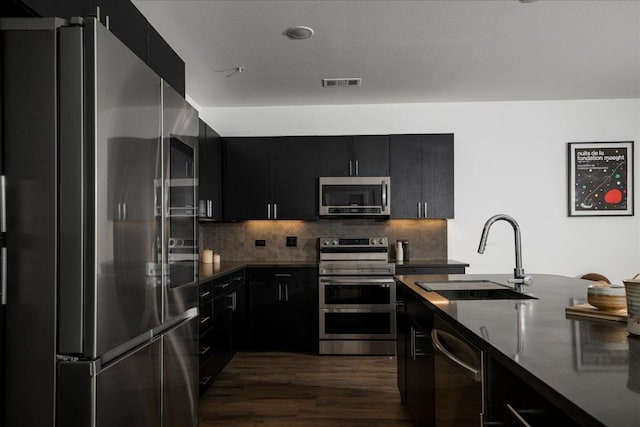 kitchen with dark cabinetry, appliances with stainless steel finishes, a sink, and visible vents