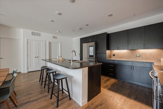 kitchen featuring dark wood finished floors, visible vents, a breakfast bar, backsplash, and smart refrigerator