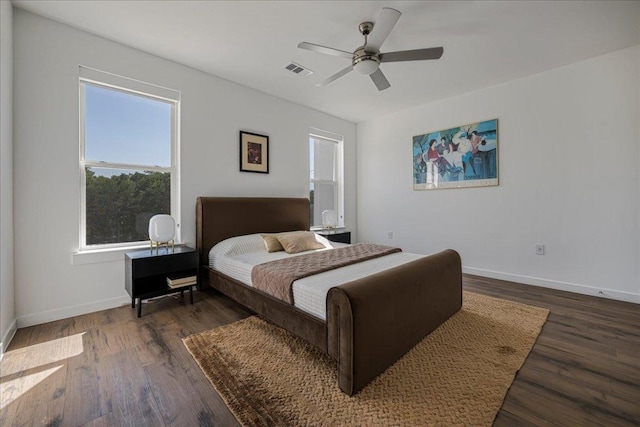 bedroom featuring wood finished floors, baseboards, multiple windows, and visible vents