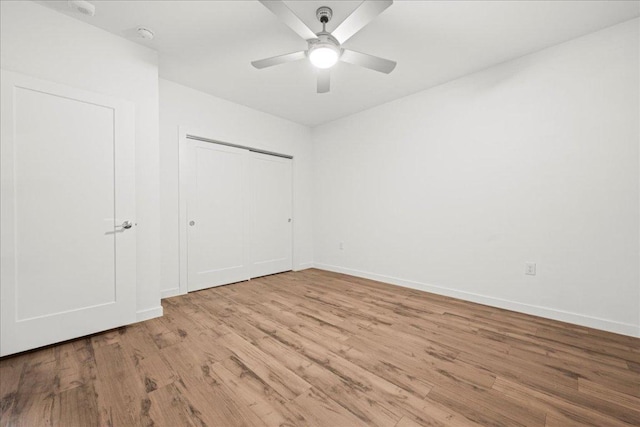 unfurnished bedroom with a closet, baseboards, a ceiling fan, and wood finished floors