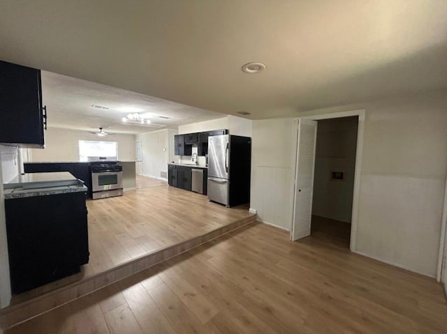 606 Springdale Rd, Austin, TX 78702 - kitchen featuring appliances with stainless steel finishes, light wood-style flooring, dark cabinetry, and ceiling fan