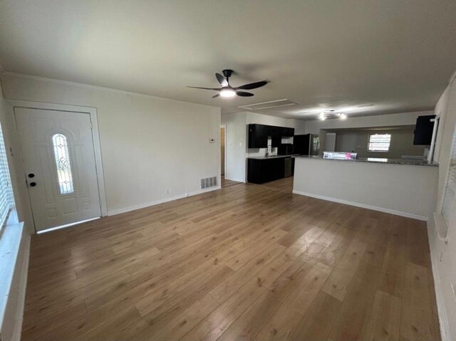 606 Springdale Rd, Austin, TX 78702 - unfurnished living room featuring a ceiling fan, light wood-style floors, and baseboards