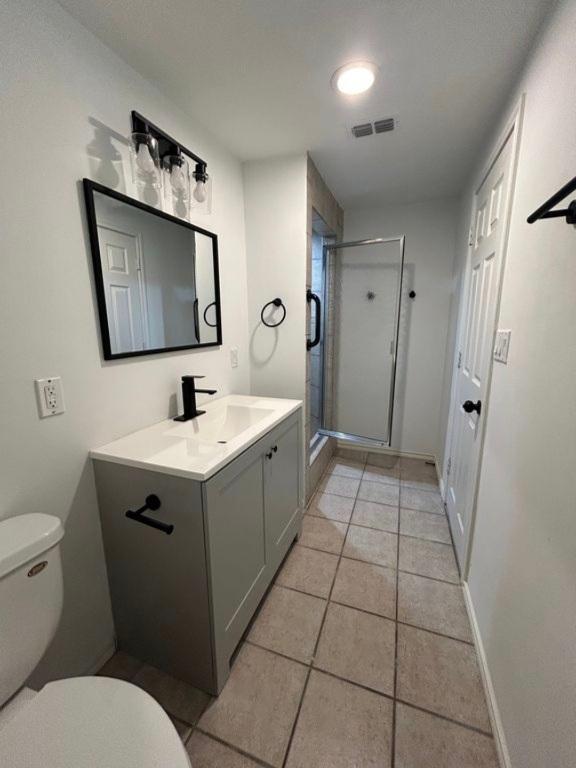 606 Springdale Rd, Austin, TX 78702 - full bathroom featuring vanity, toilet, a stall shower, and tile patterned floors
