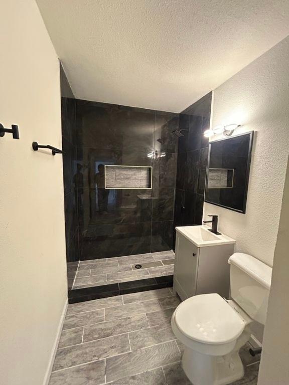 606 Springdale Rd, Austin, TX 78702 - full bathroom with toilet, vanity, a walk in shower, and a textured ceiling