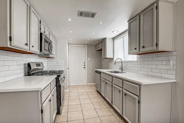 2109 Delvin Ln, Austin, TX 78728 - kitchen with stainless steel appliances, gray cabinetry, a sink, light countertops, and decorative backsplash