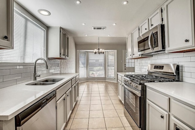 2109 Delvin Ln, Austin, TX 78728 - kitchen featuring appliances with stainless steel finishes, a sink, a chandelier, tasteful backsplash, and light tile patterned floors
