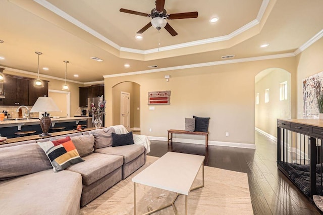 611 Algerita Dr, Georgetown, TX 78628 - living room featuring arched walkways, dark wood-style floors, recessed lighting, ceiling fan, and a tray ceiling
