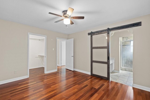 3504 Valley Pike Rd, Cedar Park, TX 78613 - unfurnished bedroom featuring wood finished floors, a spacious closet, a barn door, a closet, and ensuite bath