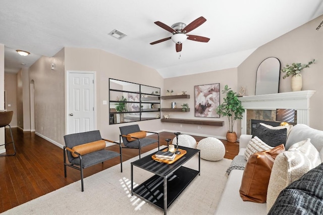 living room featuring visible vents, baseboards, ceiling fan, wood finished floors, and a glass covered fireplace