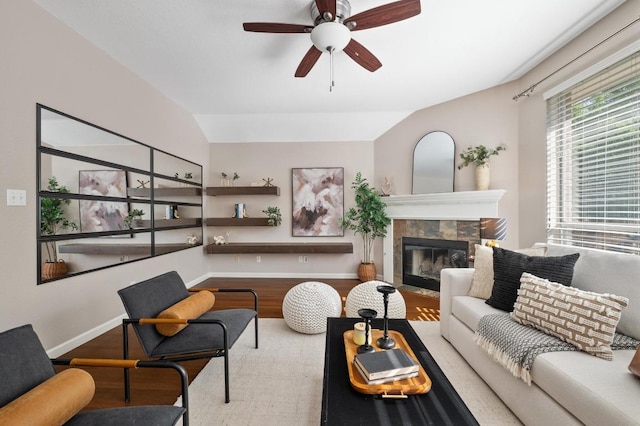living room with baseboards, a ceiling fan, a fireplace, and lofted ceiling