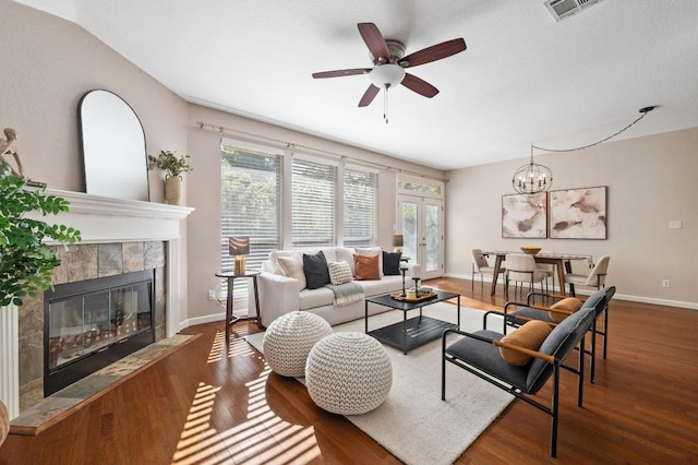 living room with visible vents, baseboards, a ceiling fan, a fireplace, and wood finished floors