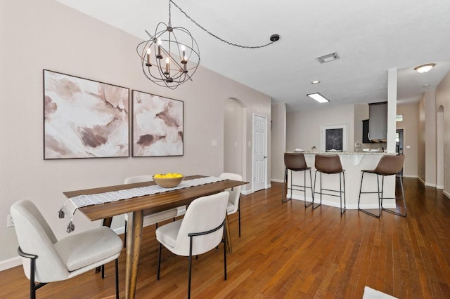 dining room featuring arched walkways, visible vents, baseboards, and wood finished floors