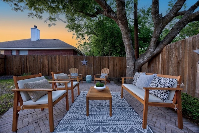 patio terrace at dusk featuring an outdoor living space and a fenced backyard