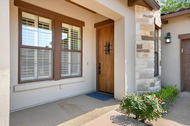 doorway to property with stucco siding and stone siding