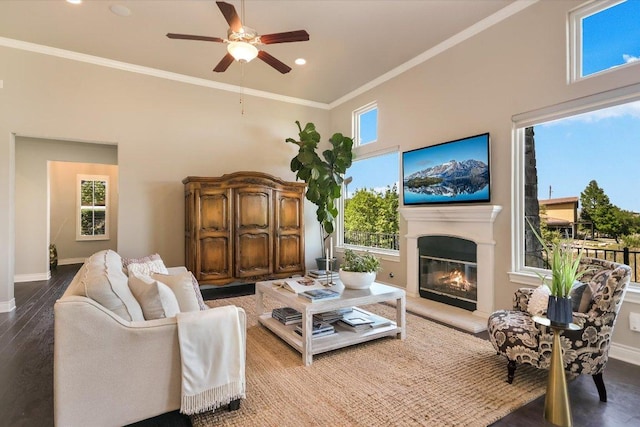 living room featuring a healthy amount of sunlight, baseboards, ceiling fan, and a glass covered fireplace