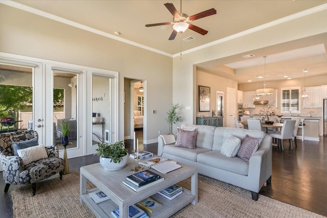 living area featuring crown molding, visible vents, dark wood-style floors, french doors, and ceiling fan with notable chandelier