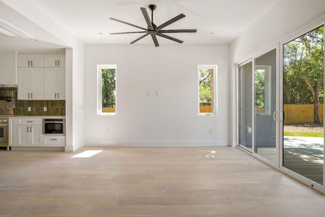 unfurnished living room with light wood-style flooring, ceiling fan, and baseboards