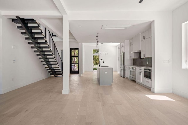 interior space with a sink, baseboards, stairway, and light wood-style flooring