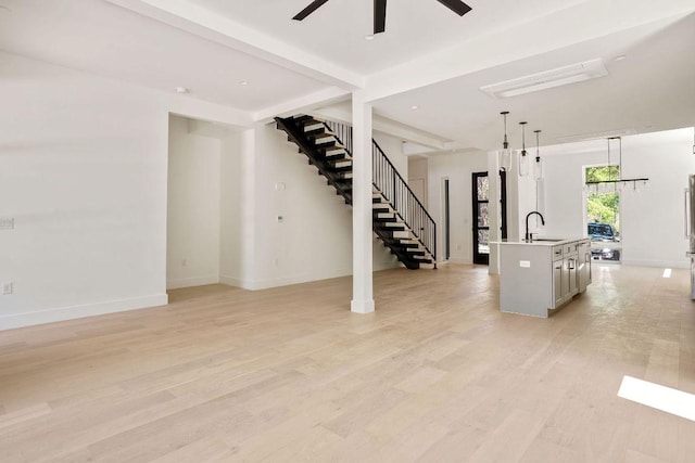 living room featuring light wood-style flooring, ceiling fan, stairway, and baseboards