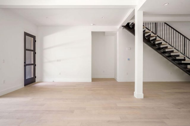below grade area featuring stairway, light wood-style flooring, and baseboards
