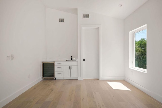 unfurnished room featuring wet bar, vaulted ceiling, visible vents, a sink, and beverage cooler